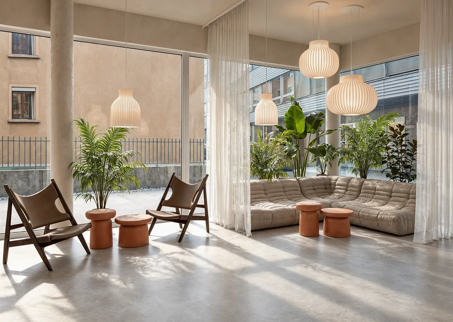 Lounge mit modularem Polstersofa, Klappstühlen aus Leder und Terrakotta-Hockern am Fenster zum Innenhof